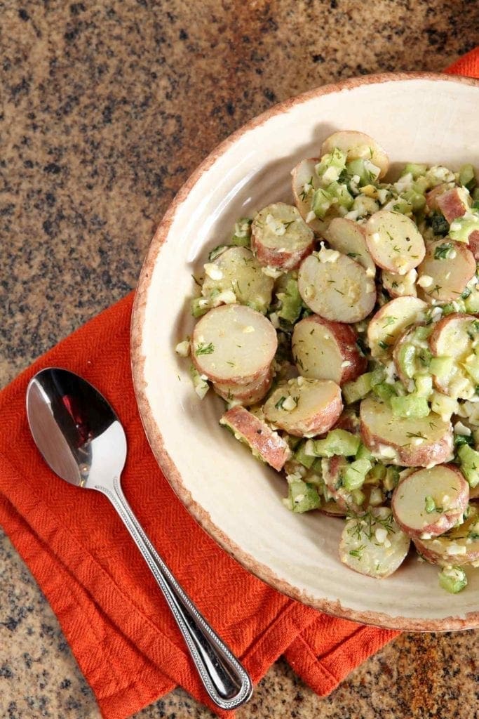 A bowl of No Mayo Potato Salad sits on a granite countertop, ready for serving