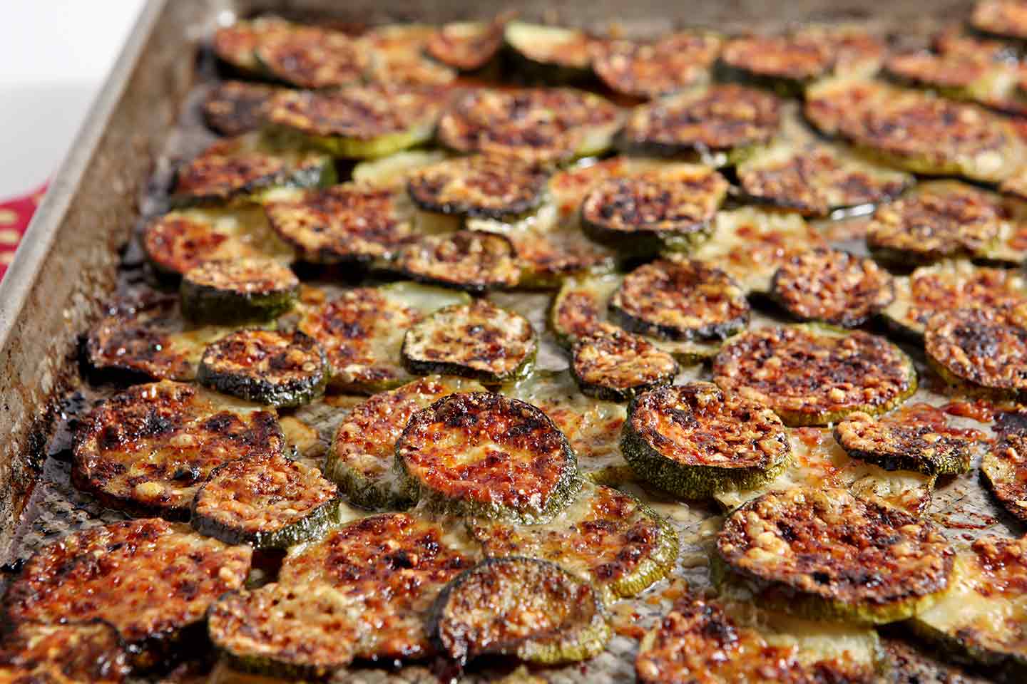 Close up of baked and broiled parmigiano reggiano zucchini in baking sheet 