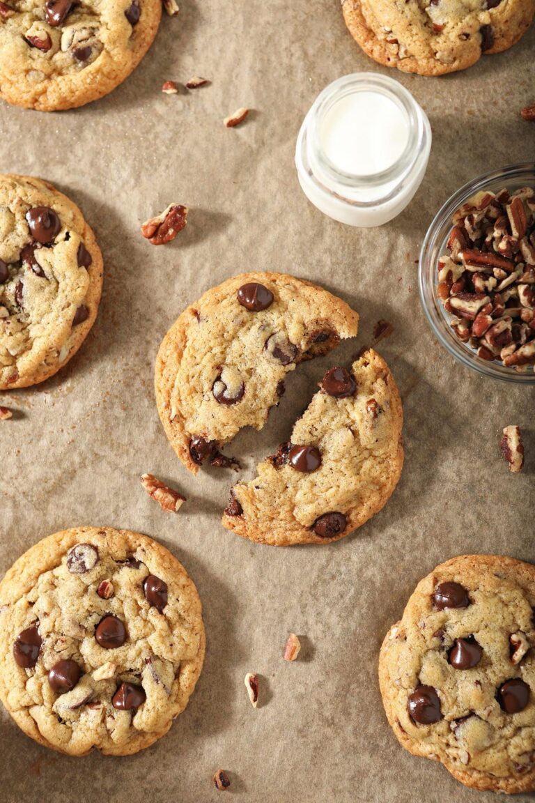 Classic Pecan Chocolate Chip Cookies on a pan with a glass of milk and pecan pieces