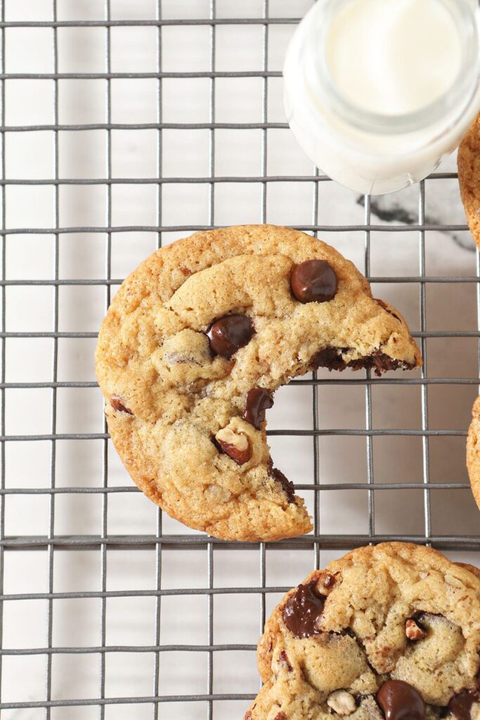 A bitten-into chocolate chip cookie on a cooling rack