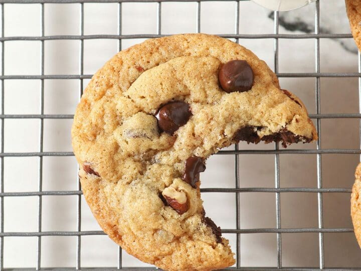 A bitten-into chocolate chip cookie on a cooling rack
