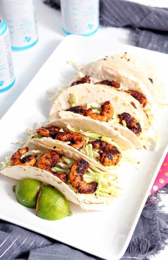 blackened shrimp tacos on a white plate with limes