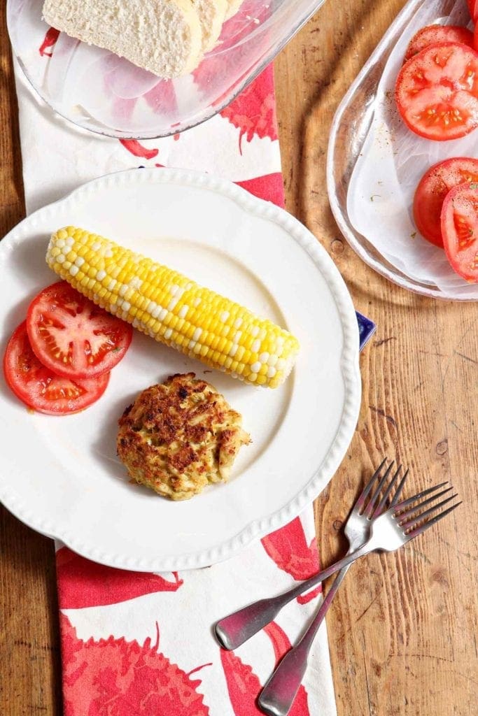 Plate of crab cake, corn on the cob and tomatoes