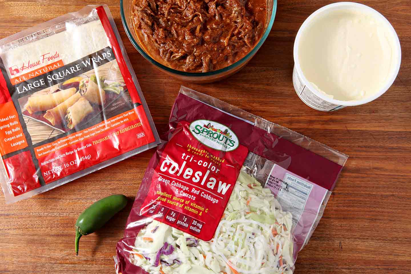 Bowl of pulled pork along side packages of ingredients 