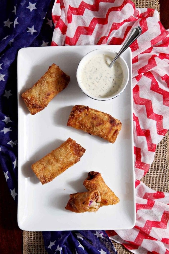 Overhead view of eggrolls on serving dish with sauce 