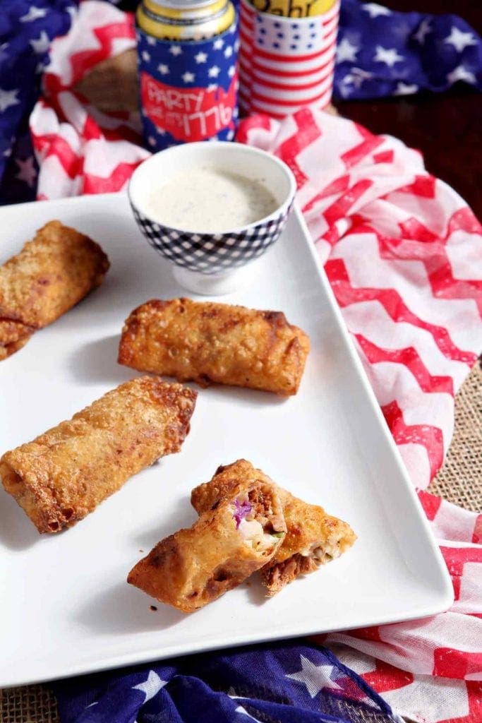 Platter of pulled pork coleslaw eggrolls with bowl of dipping sauce 