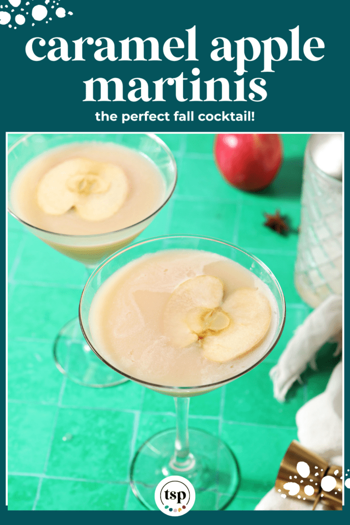 Two salted caramel apple martinis on a green tiled surface surrounded with spices and apples with the text caramel apple martinis the perfect fall cocktail