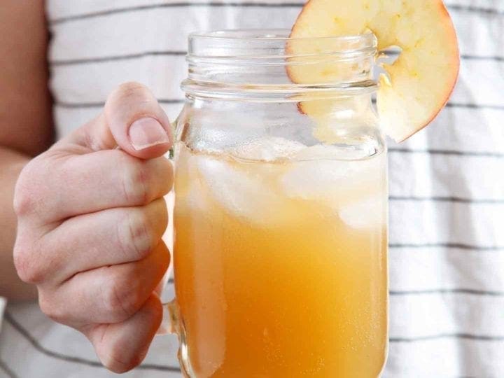 A woman holds a mason jar full of Sparkling Bourbon Pumpkin Apple Punch in her hand
