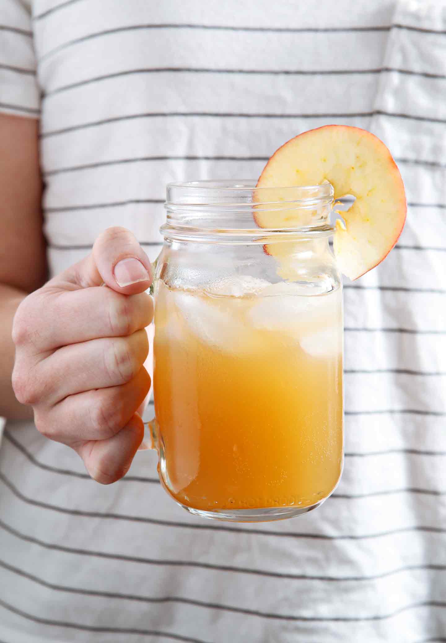 A woman holds a mason jar full of Sparkling Bourbon Pumpkin Apple Punch in her hand