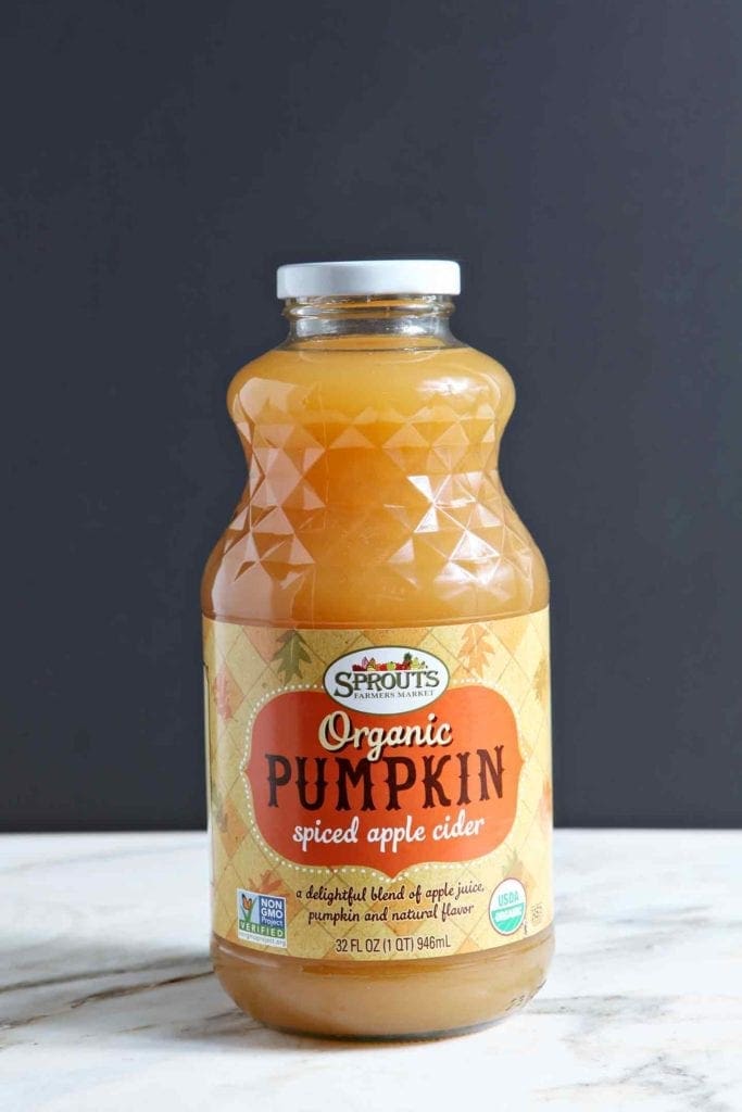 A bottle of Sprouts Organic Pumpkin Spiced Apple Cider sits on a marble backdrop.