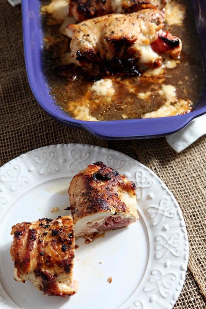 Cut chicken breast on white plate in front of blue serving dish 