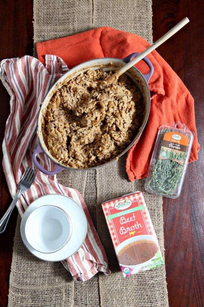 A Dutch oven full of homemade risotto sits on a table next to bowls and ingredients