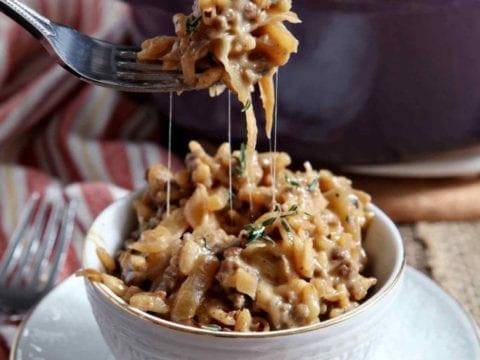 A fork lifts risotto out of a bowl