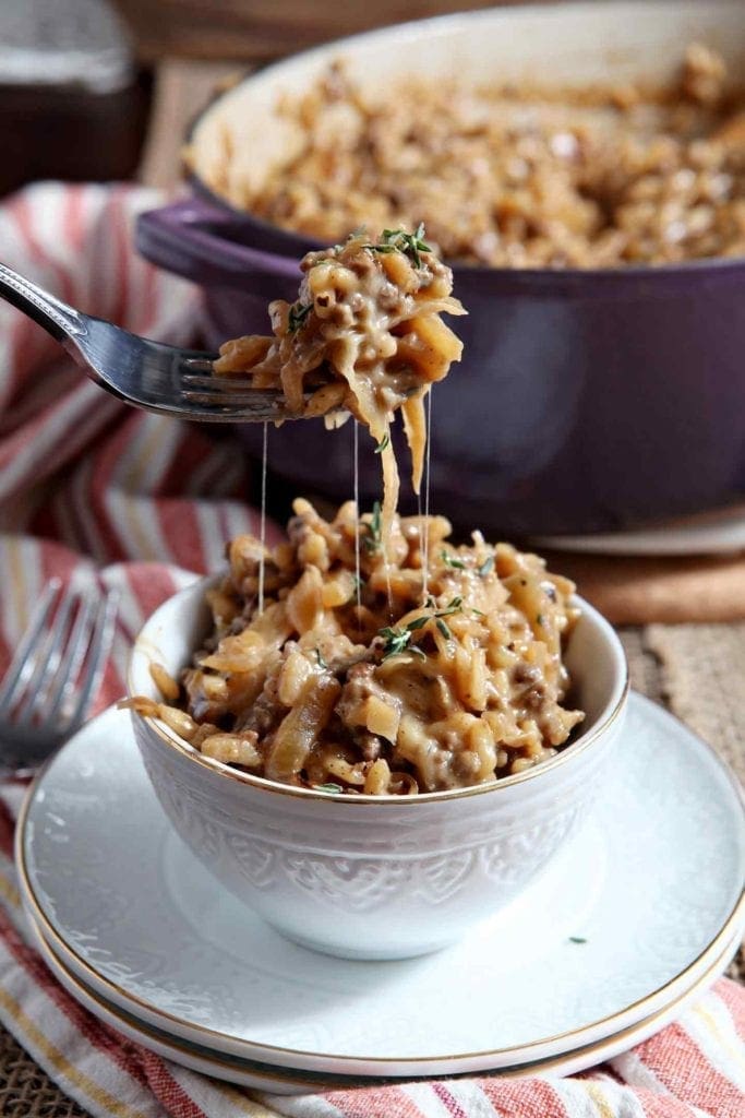 A fork lifts risotto out of a bowl