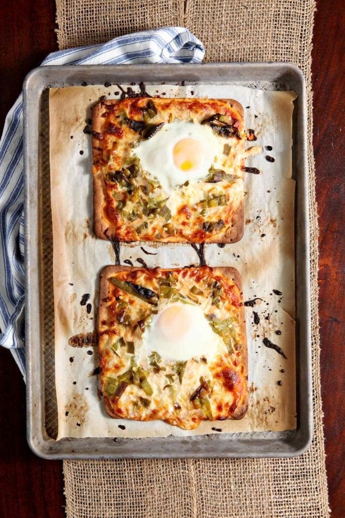 Two Hatch Chile Breakfast Flatbreads sit on a baking sheet, straight out of the oven.