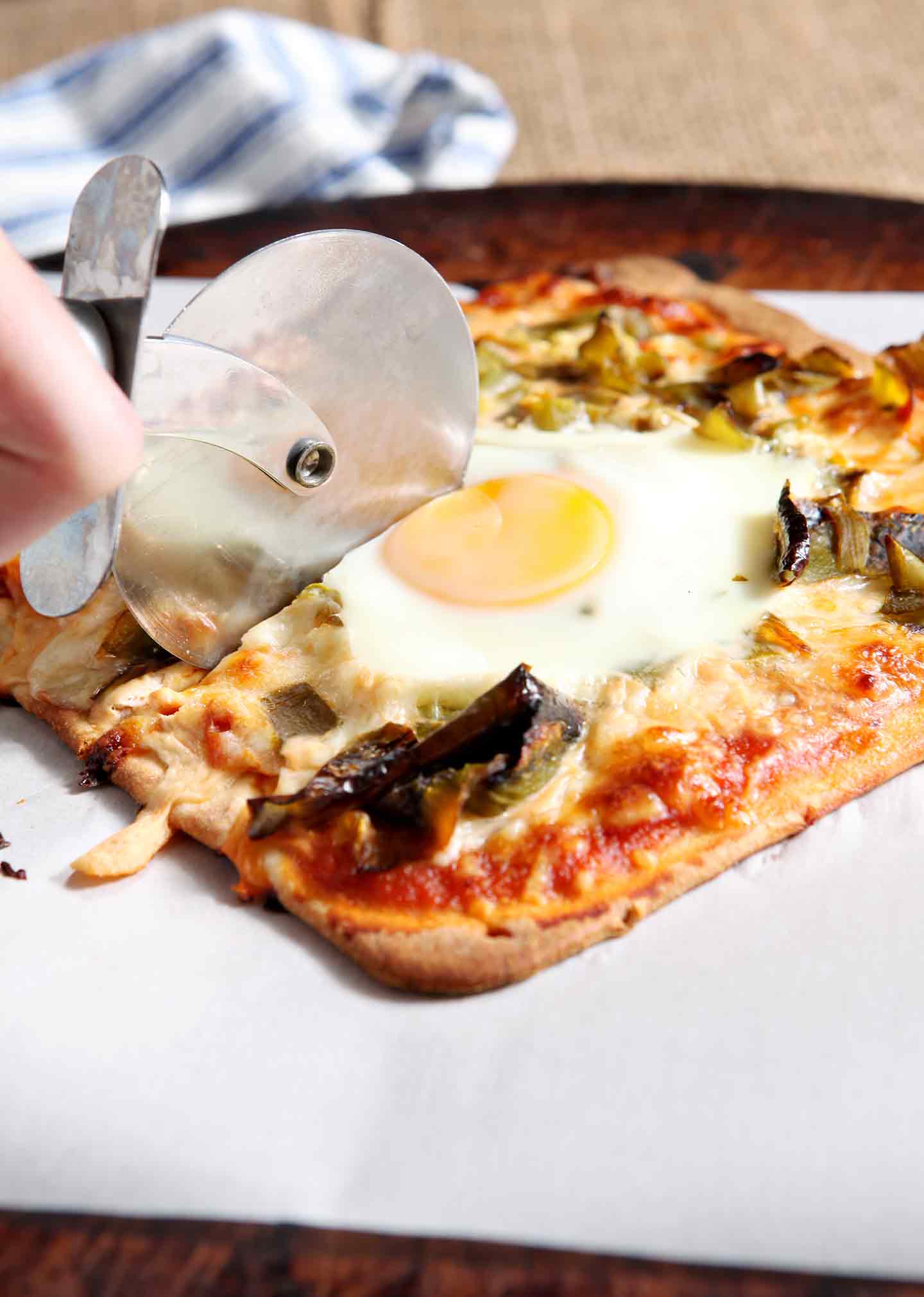 Hand cutting into flatbread with pizza cutter 