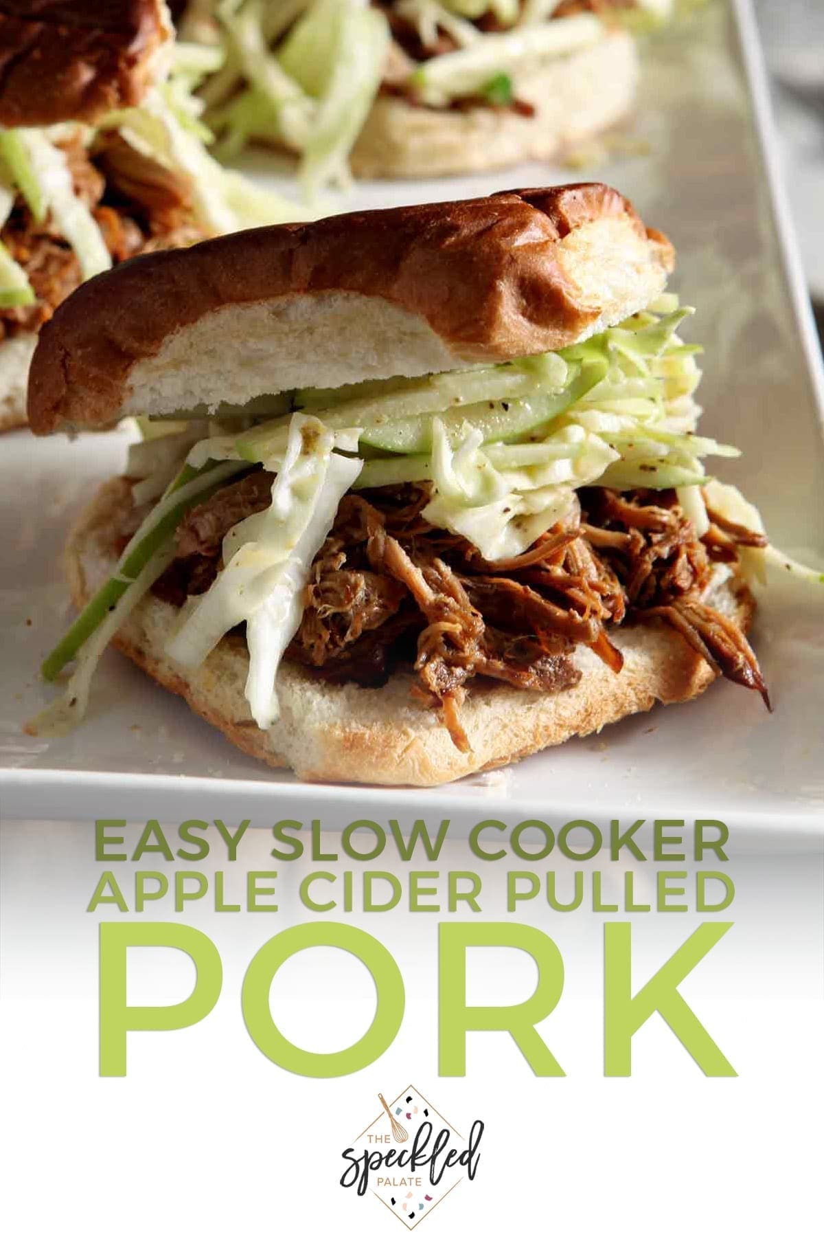 Three pulled pork sandwiches with apple slaw on a white platter with the text 'easy slow cooker apple cider pulled pork'