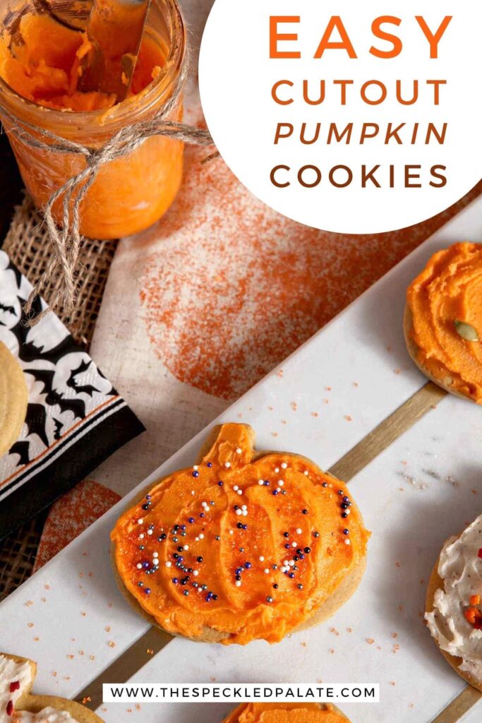 Close up of an orange iced pumpkin with sprinkles on a marble slab with the text 'easy cutout pumpkin cookies'