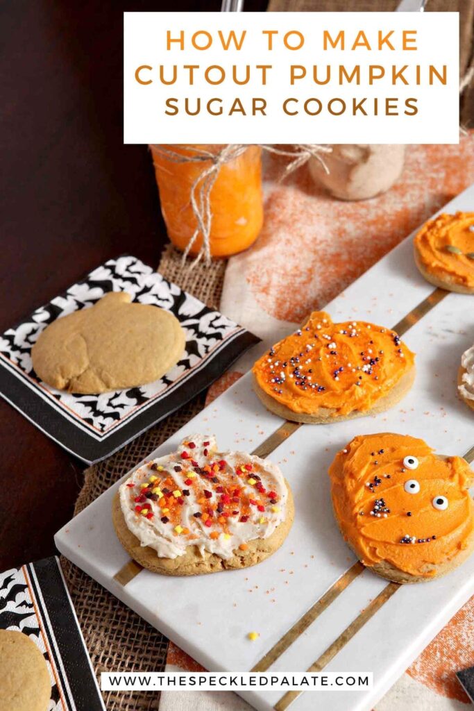 Decorated Pumpkin Sugar Cookies sit on a marble slab next to an undecorated cookie and jars of icing with the text 'how to make cutout pumpkin sugar cookies'