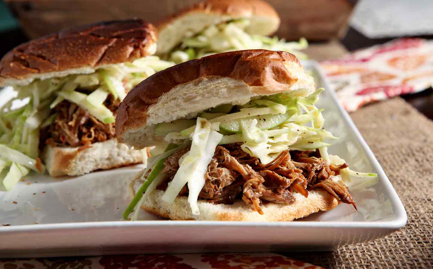 apple cider pulled pork sandwiches on a white platter