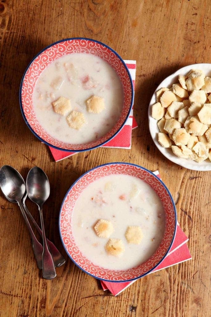 Overhead picture of 2 bowls of clam chowder on wood table 