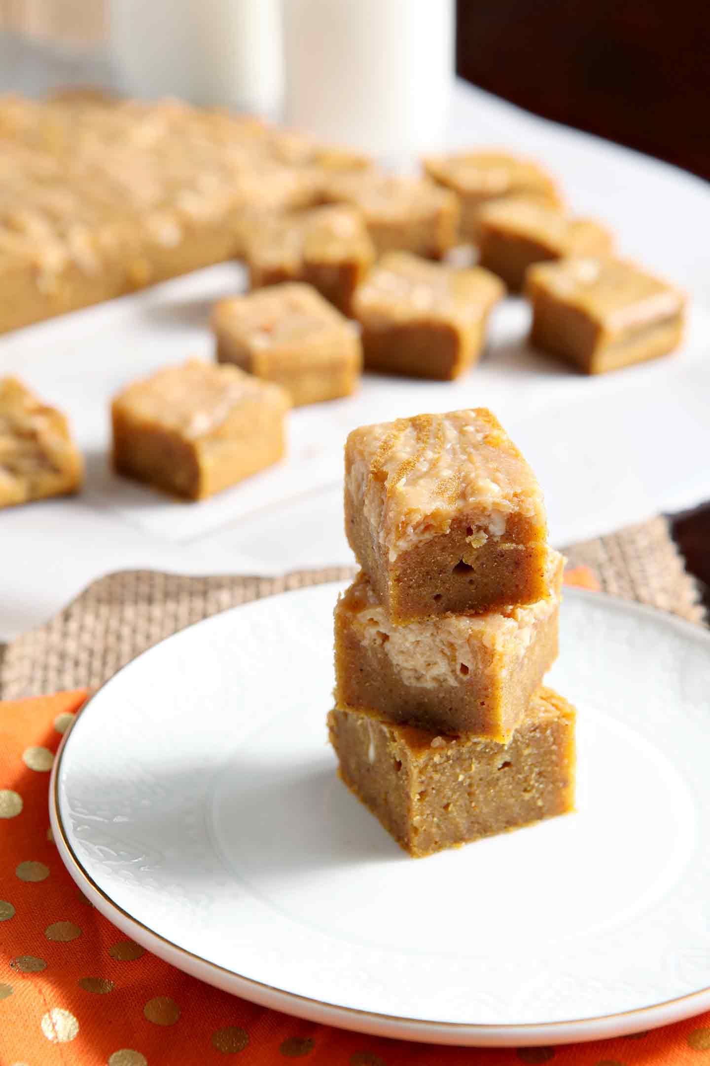 Close up of stacked blondies on a plate, with others in the background