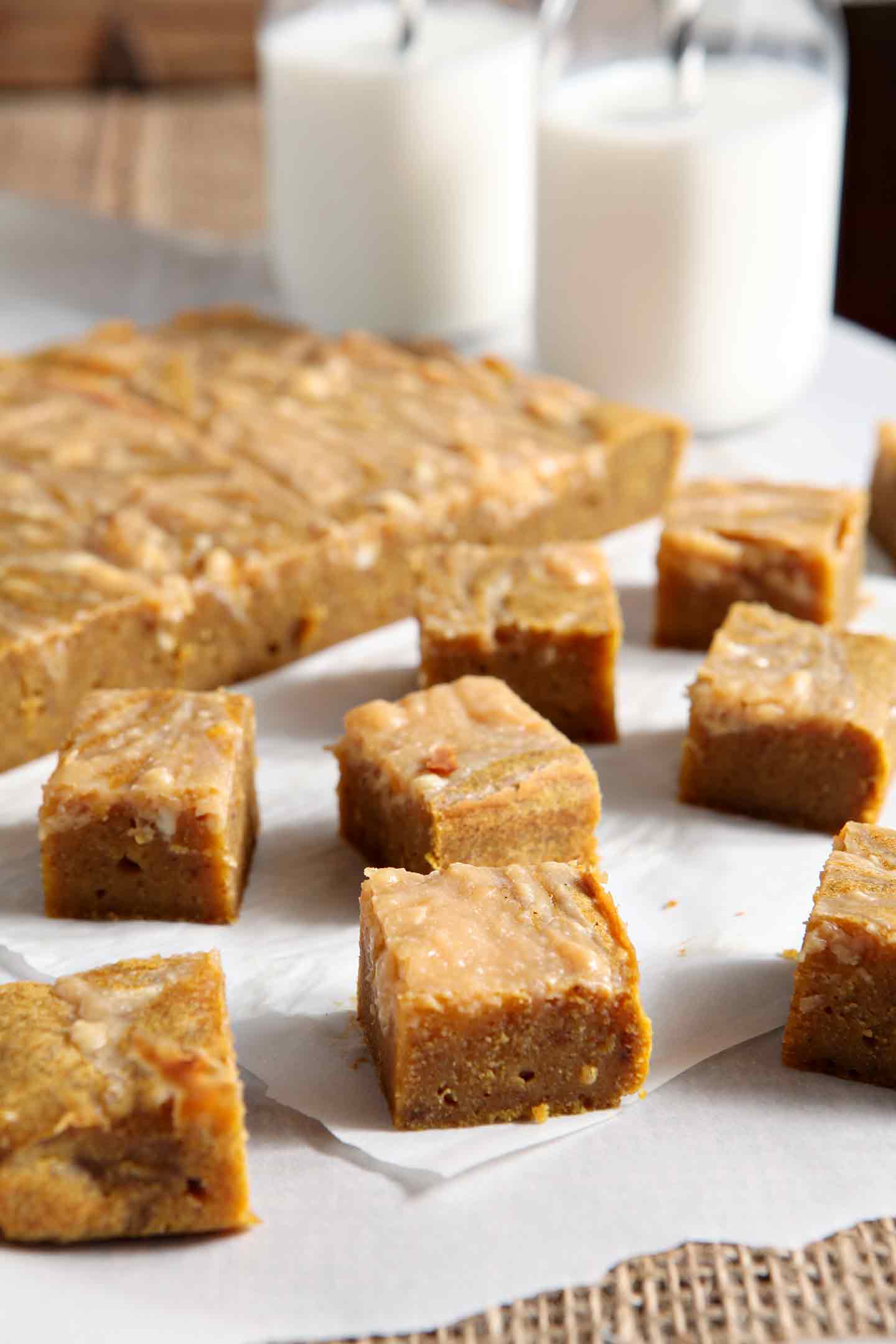 Sliced pumpkin blondies, from the side, with jugs of milk