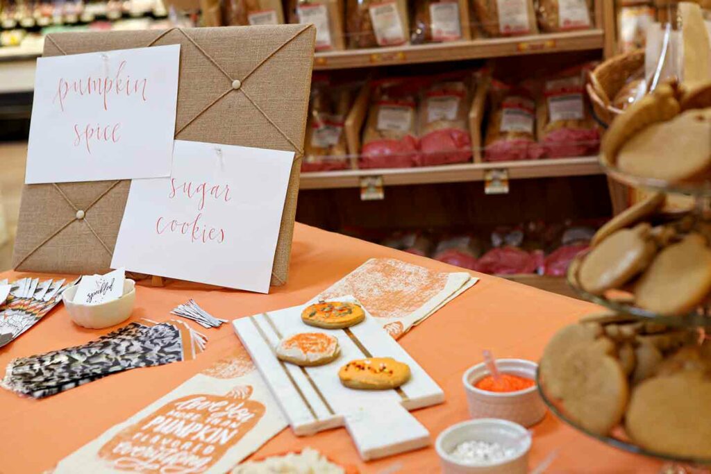 An orange-lined table inside a Sprouts with cookie decorating related items sitting on it