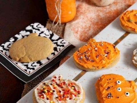 A marble platter holds several decorated Spiced Pumpkin Sugar Cookies