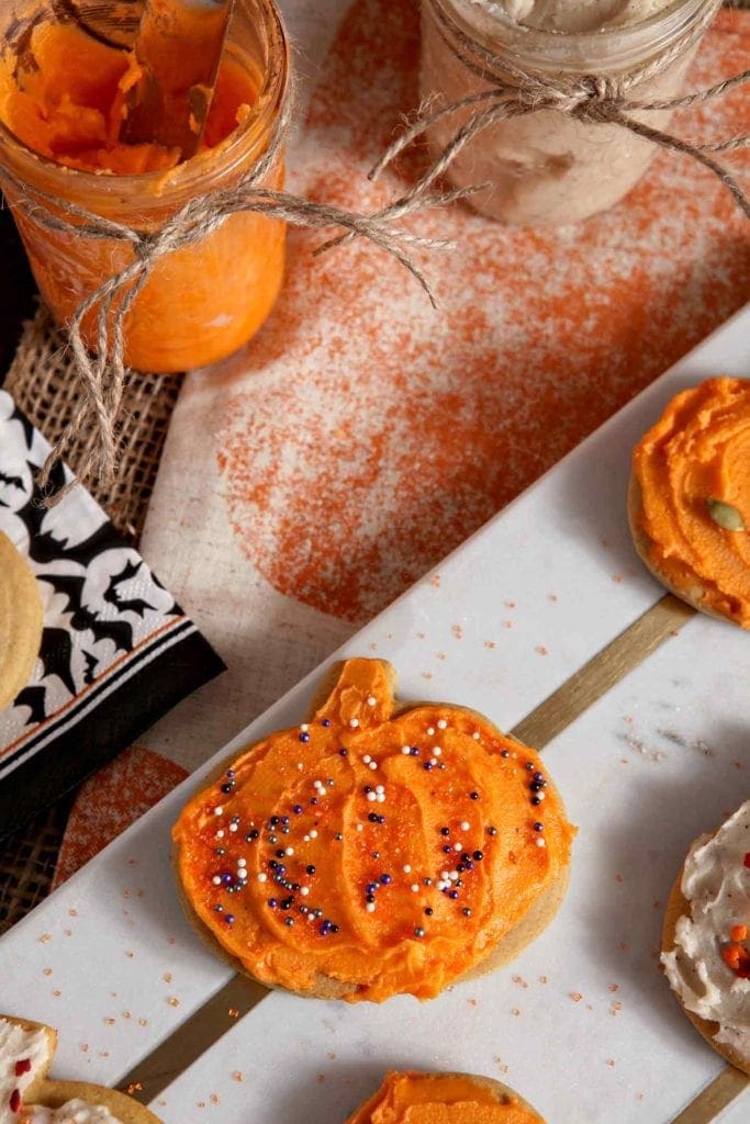 Close up of an orange iced pumpkin with sprinkles on a marble slab