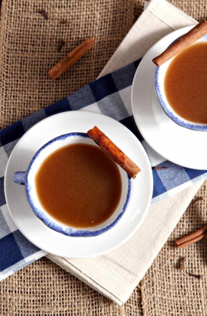 Two cups of Spiced Apple Cider, served in mugs with cinnamon sticks