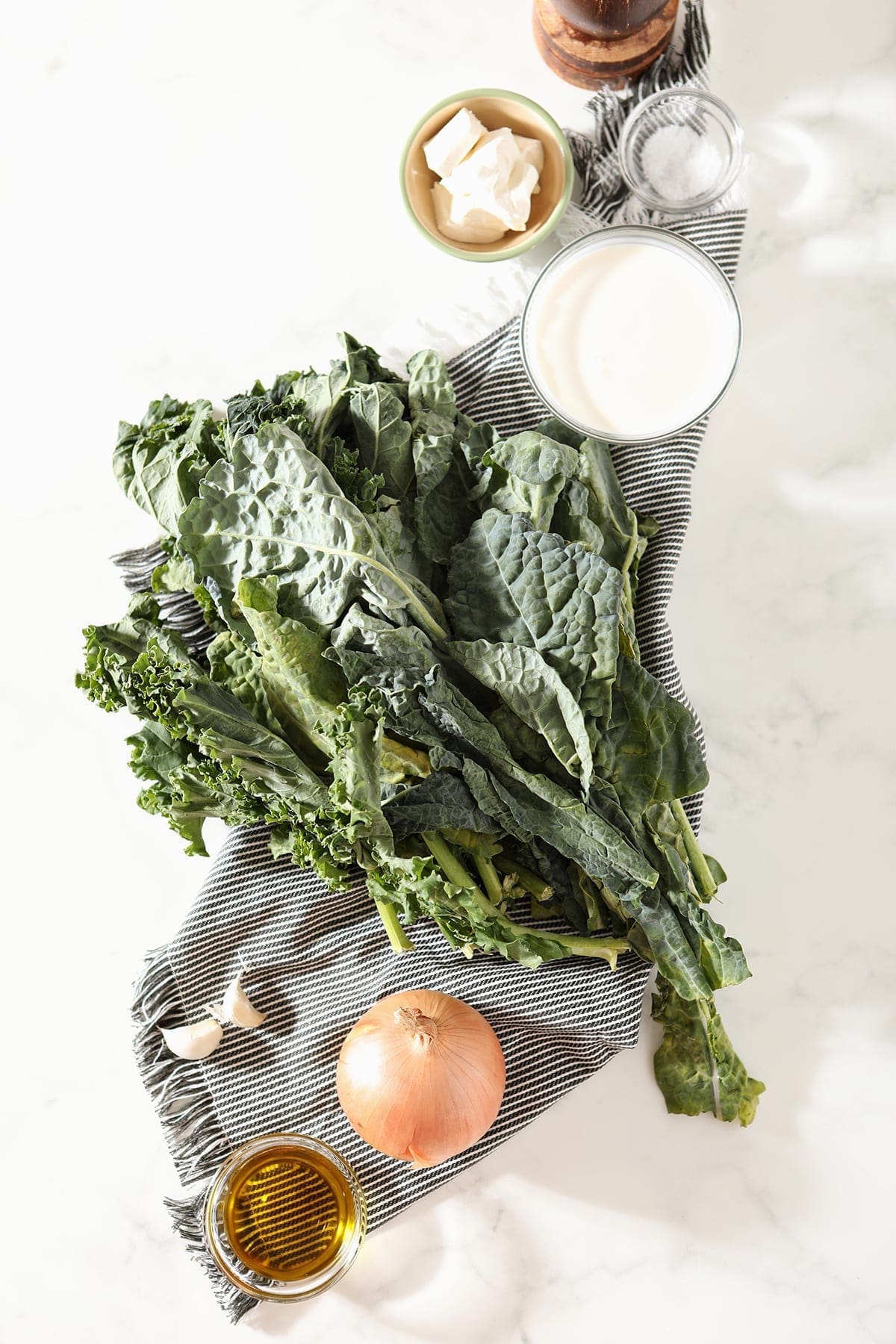 Fresh kale, onion and other ingredients on a gray striped towel