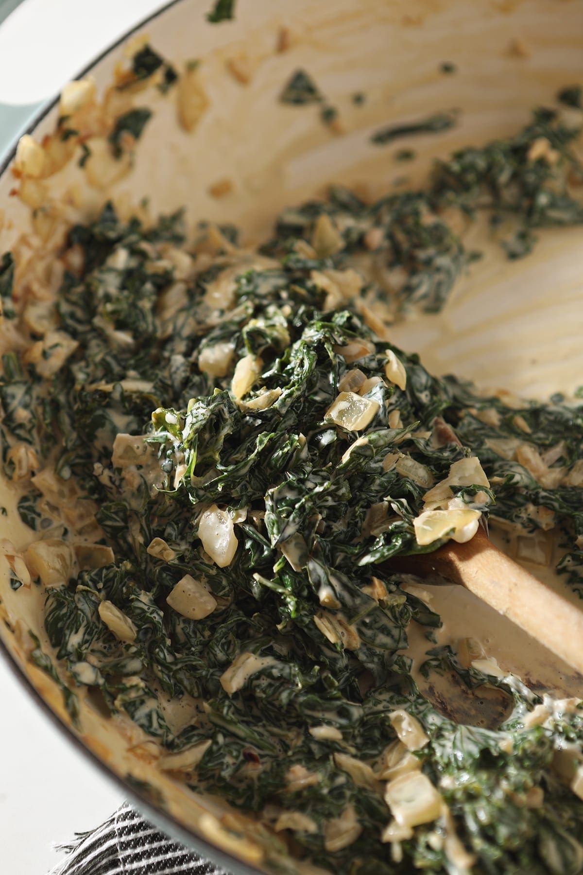 The creamy kale in a pan, after stirring the cream cheese into the mixture