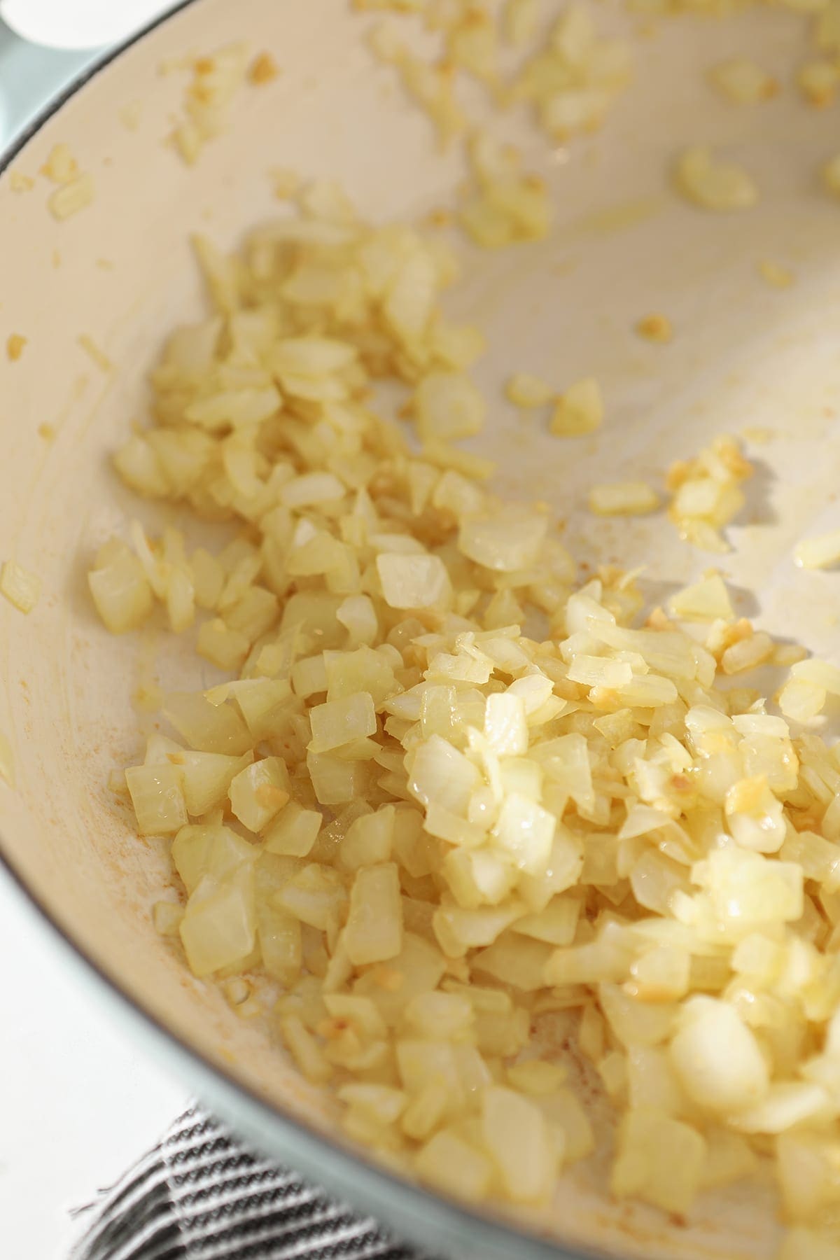 Close up of softened sauted onion and garlic in a pan