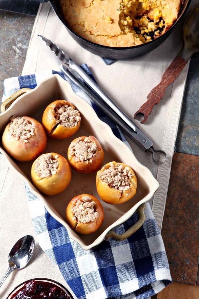 Overhead of stuffed apples with a bacon streusel, on a table with other holiday dishes