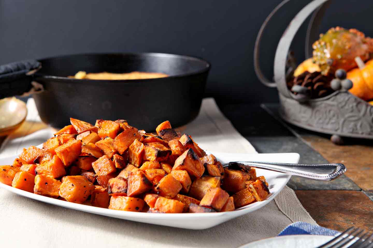 Horizontal image of Bourbon Butter Sweet Potatoes, shown on a white plate