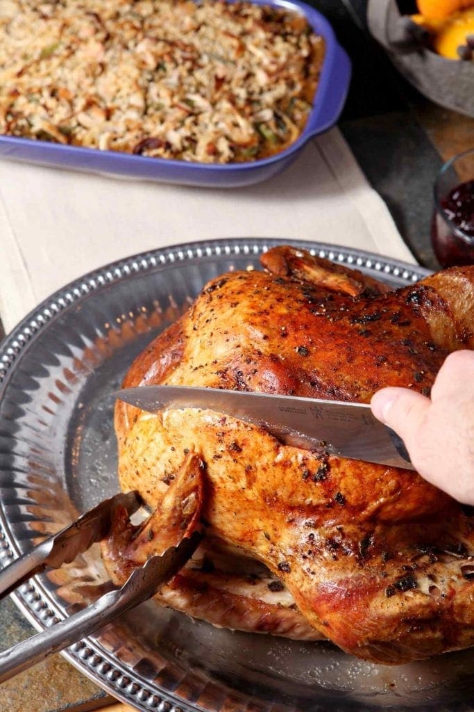 A whole roasted Browned Butter Sage Turkey is cut into with a knife.