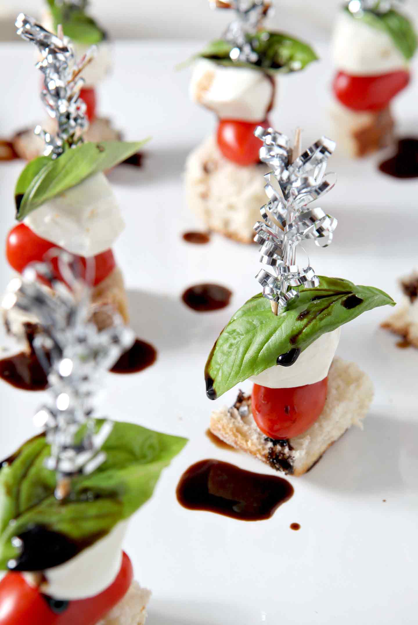 caprese skewers on a white plate with balsamic