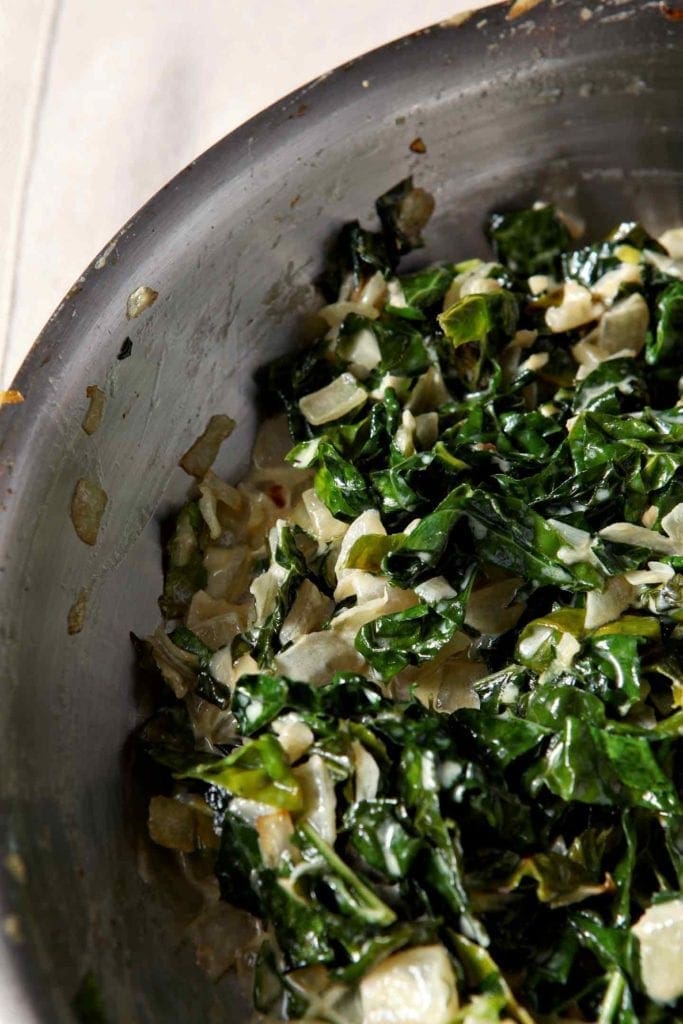 Creamy kale in a silver skillet, on a beige towel