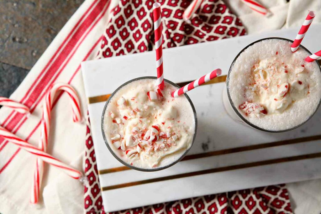 Overhead of two ice cream creations on a marble slab surrounded by peppermints and red cloth