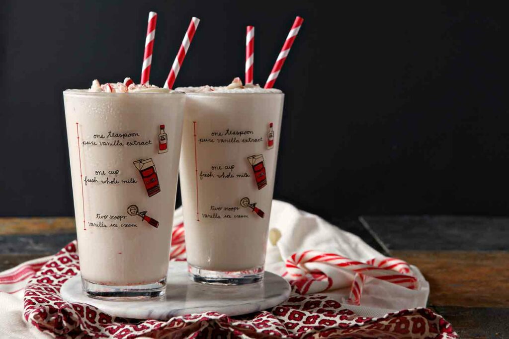 Two pint glasses holding pink milkshakes sit on a marble serving tray, ready for enjoying