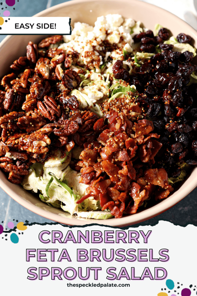 A brussels sprouts salad recipe in a large red bowl on a blue tiled surface before tossing with the text Cranberry Feta Brussels Sprout Salad