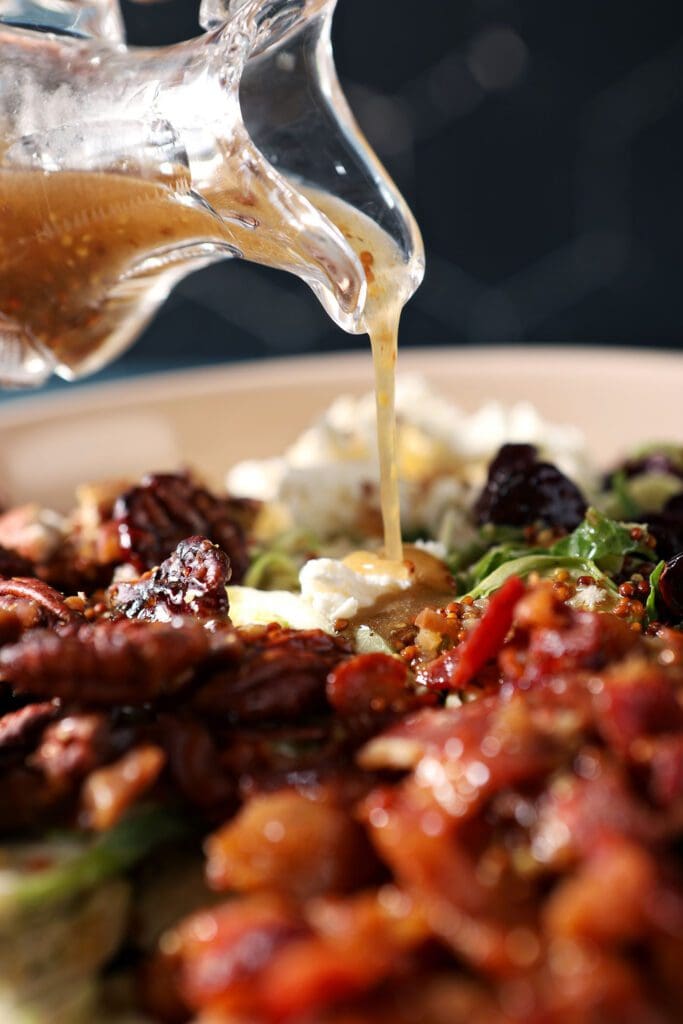 Hot bacon vinaigrette pours on top of a bowl of salad