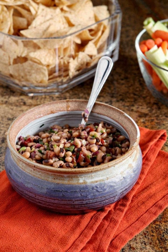 Bowl of Black Eyed Pea Dip served with chips and vegetable sticks