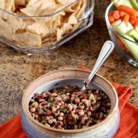 Bowl of Black Eyed Pea Dip served with chips and vegetable sticks