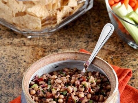 Bowl of Black Eyed Pea Dip served with chips and vegetable sticks 