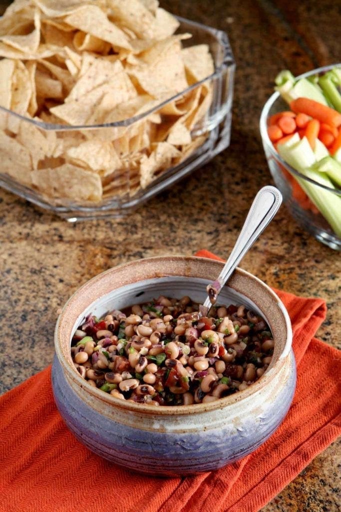 Bowl of Black Eyed Pea Dip served with chips and vegetable sticks 