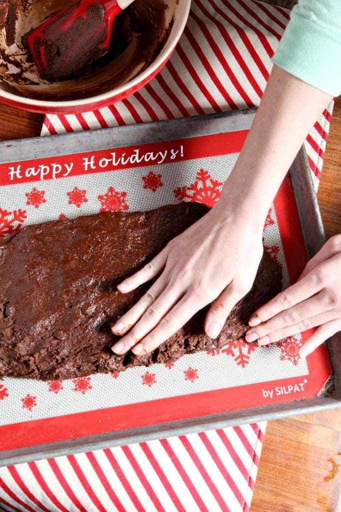 Hand patting down Gingerbread Biscotti batter on holiday silpat on baking sheet 