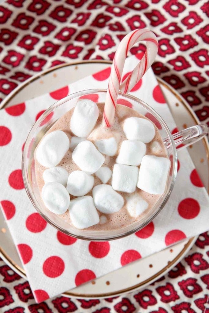 Overhead shot of hot chocolate in mug with marshmallows and candy cane