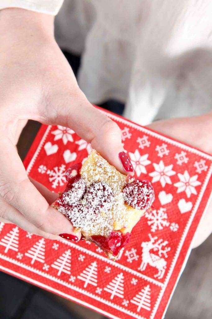 Hand holding Orange Cranberry Bar over red holiday napkin